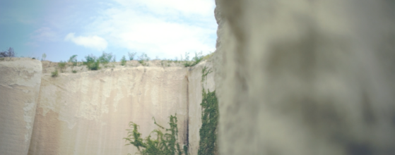 Zsuzsa és Gareth esküvői fotója a Bolyki pincészet szőlőhegyi panorámájával, kő falak között a meleg napsütésben