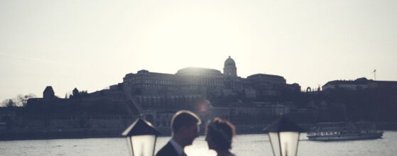 Olcsi és Józsi az esküvői fotón a Columbus Hajó fedélzetén, Budavár panorámájával a háttérben Duna-parton este