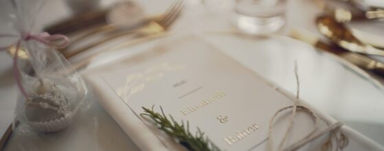 Ein elegant gedeckter Tisch beim Holler Weingut Scheune mit dem Menü von Elisabeth und Rainer, verziert mit Rosmarin – ein feines Detail aus ihrem Hochzeitsfilm.