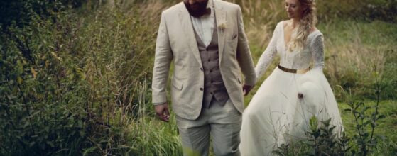 Gilda und Martin Hand in Hand gehen durch das hohe Gras beim Streitdorf Kreuzstadl, ganz in ihre Gedanken vertieft – ein sehr emotionaler Moment aus ihrem Hochzeitsfilm.