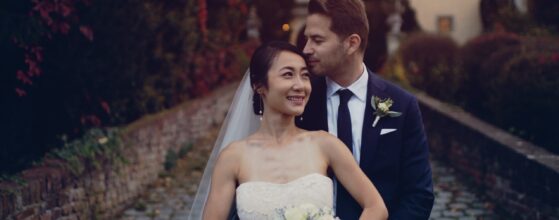 Emma lehunyt szemmel lehajtja den Kopf, während Gerald sie von hinten umarmt im herbstlichen Garten von Schloss Obermayerhofen – ein emotionaler Moment aus ihrem Hochzeitstrailer.