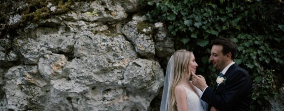 Anita és Ádám a tihanyi Echo étterem sziklái előtt állnak egymáshoz közel, háttérben a Balaton-parti sziklafal – egy meghitt pillanat a tihanyi esküvői filmjükből.