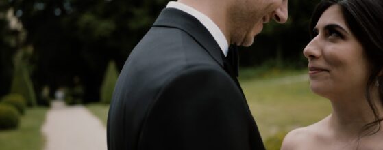 Maral und Raphael lachen miteinander im Park von Schloss Obermayerhofen, während sie sich gegenüberstehen – ein spontaner, fröhlicher Moment aus ihrem Hochzeitsfilm.