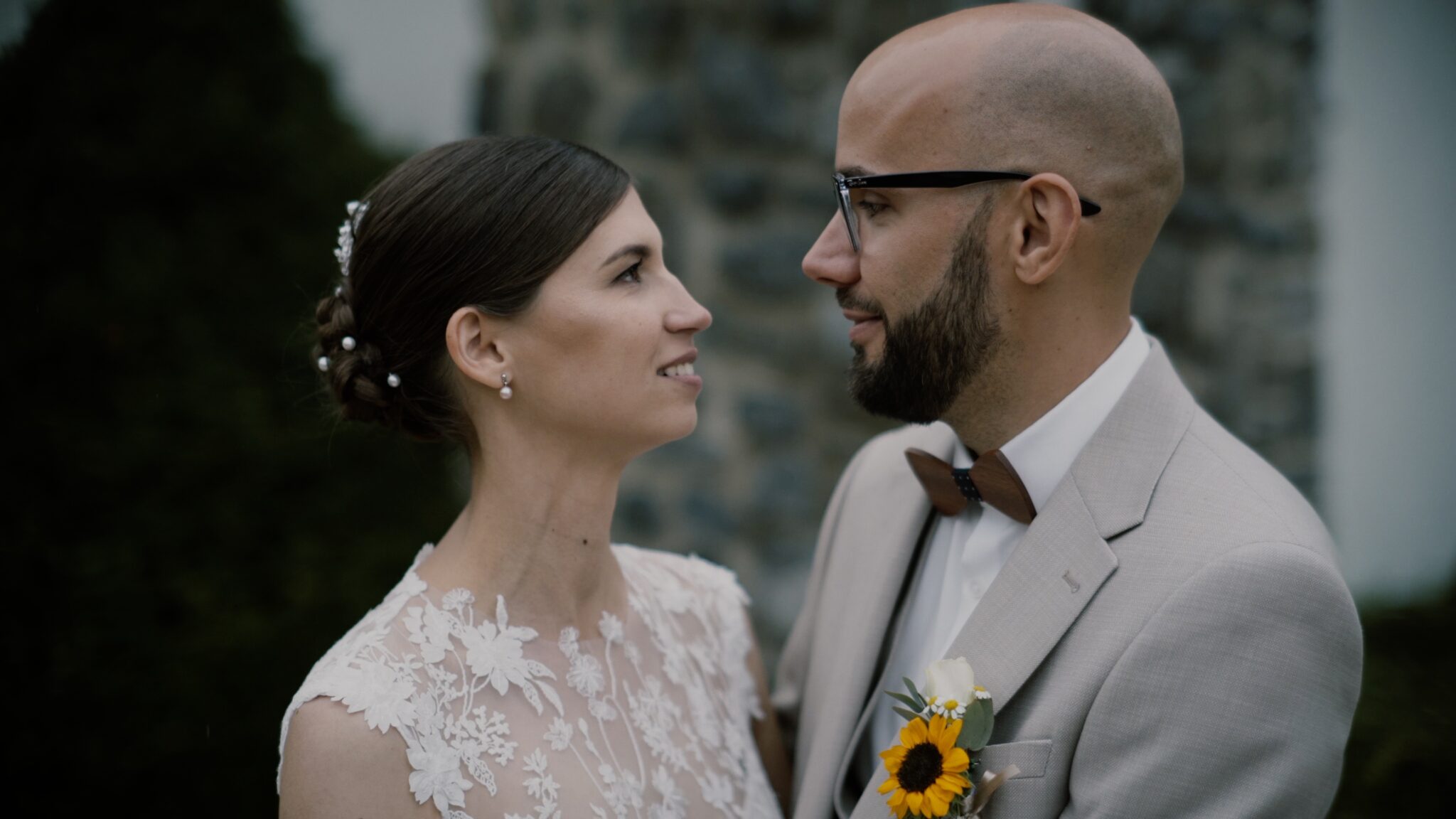 Kata és Gábor egymás felé fordulva állnak a zalacsányi Batthyány Kastélyszálló parkjában, elegáns nyári esküvői pillanat az esküvői filmjükből.