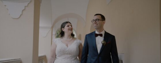 Johanna und Ulrich gehen Hand in Hand durch die Arkaden von Schloss Obermayerhofen in der Steiermark – ein ruhiger Moment aus ihrem Hochzeitsvideo.