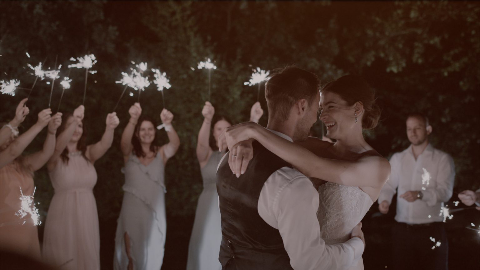 Patricia und Josef gehen nach der Trauung durch das Spalier ihrer Gäste beim Berghotel Tulbingerkogel, alle klatschen und feiern – ein fröhlicher Moment aus ihrem Hochzeitsfilm.