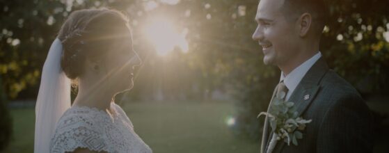 Zsófi és Tomi egymással szemben állnak a Forster Vadászkastély parkjában, a lemenő nap fénye ragyog mögöttük – egy meghitt pillanat az esküvői filmből.