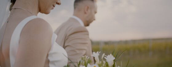 Bride holding a white and green bouquet while walking with the groom between the vineyards at Rókusfalvy Birtok in Etyek – detail from Móni and Levi’s wedding film.