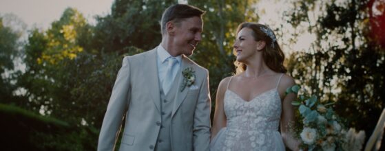 Melinda és Attila kézen fogva sétálnak a Völgy Major kertjében Verőcén, naplementés esküvői film jelenet.”