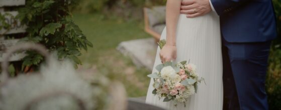 Karin und Florian im Garten des Landgasthaus zur Krone in Gaaden, die Braut hält ihren natürlichen Brautstrauß – ruhiger Moment aus dem Hochzeitsfilm.
