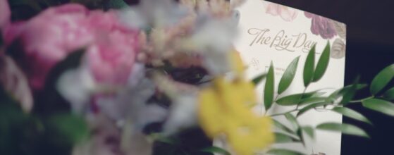 Floral wedding invitation with The Big Day lettering tucked into Bronwen’s bouquet at Lough Eske Castle in Ireland, a soft detail from their wedding film.