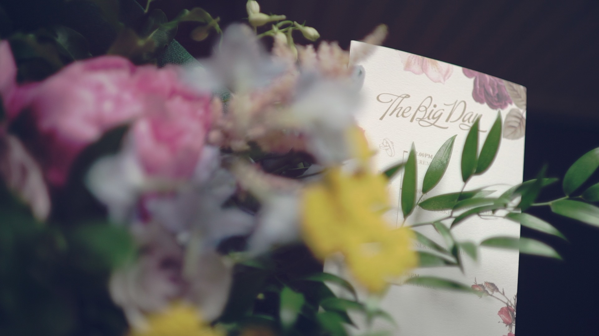 Floral wedding invitation with The Big Day lettering tucked into Bronwen’s bouquet at Lough Eske Castle in Ireland, a soft detail from their wedding film.