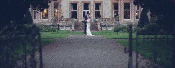 Story-driven wedding videographer Ireland Bride Caoimhe and groom Michael stand together in front of the stunning Castle Leslie Estate manor house on their wedding day – captured in their cinematic wedding teaser video
