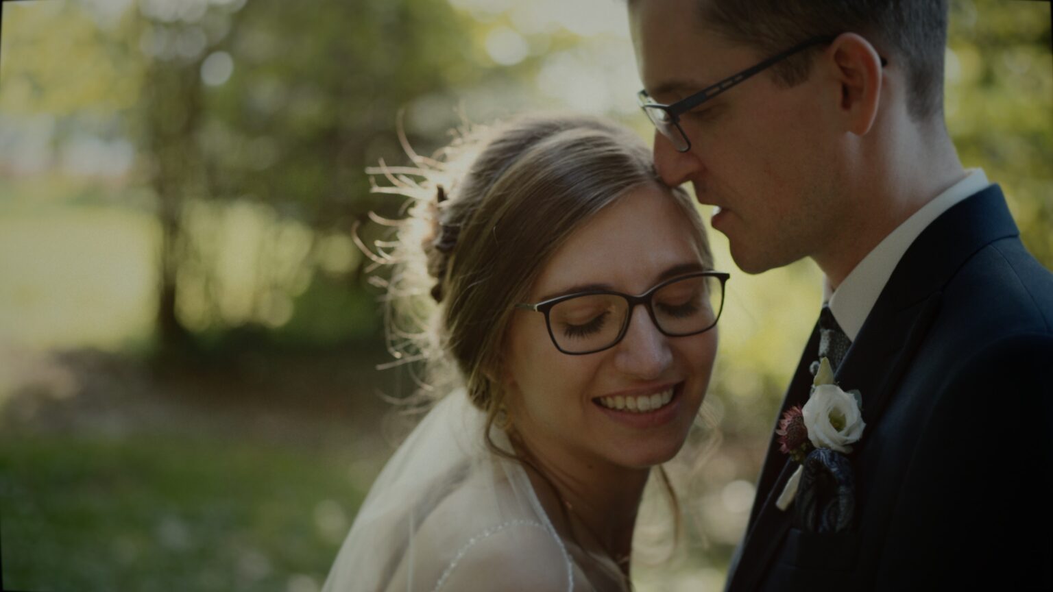 Corina und Martin stehen Stirn an Stirn im Garten des Winzerhotel Kolleritsch in Tieschen, weiches Nachmittagslicht hinter ihnen – ein leiser Moment aus ihrem Hochzeitsvideo.