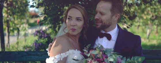 Brautpaar Corinna und Leopold sitzt mit einem großen Blumenstrauß auf einer Gartenbank beim Holler Weingut Scheune in der Südsteiermark