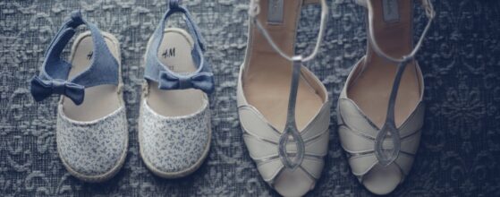 Hochzeitschuhe von Dani und Jürgen liegen nebeneinander auf einem gemusterten Teppich beim Streitdorf Kreuzstadl – weiße Brautenschuhe und braune Herrenelschuhe