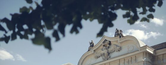 Barocke Fassade des Schlosses Halbturn mit Adlerrelief und Statuen vor blauem Himmel im Hochzeitstrailer von Hanna und Rainer Baroque Architecture Wedding Teaser Halbturn