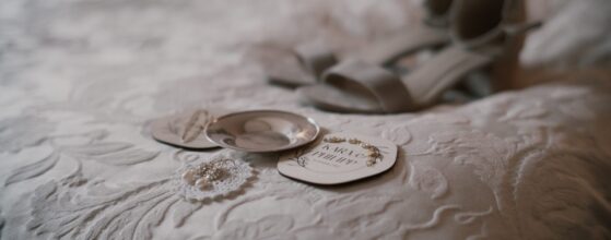 Wedding details of Kara and Philipp laid out on a soft textured bedspread at Schloss Obermayerhofen – earrings, rings and shoes ready for their destination wedding.