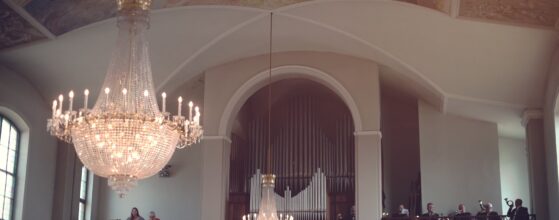 Großer funkelnder Kronleuchter und Orgel auf der Empore in der Kirche bei der Hochzeit von Katharina und Jürgen Burgenland Zicksee hochzeit film
