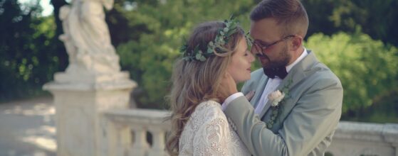 Marina und Dieter stehen eng umschlungen vor der Balustrade im Garten von Schloss Niederleis, im Hintergrund eine Statue und viel Grün Mistelbach hochzeit film