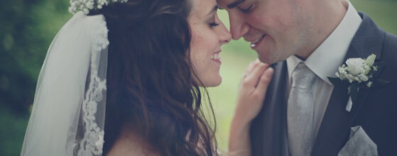 Laxenburg hochzeit film Michelle und Florian stehen sich nah gegenüber, ihre Stirnen berühren sich, Michelle trägt einen weißen Schleier und Florian einen grauen Anzug mit weißer Boutonniere.