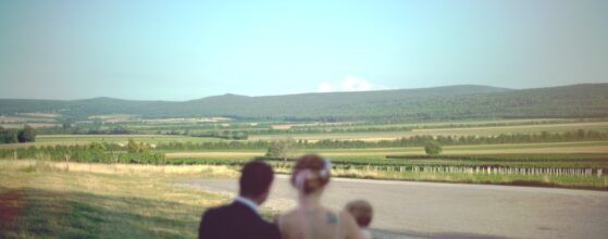 Nadine und Zoltan stehen mit ihrer Tochter Miriam auf einer Wiese beim Liszt Weingut und blicken auf die weiten Felder und Hügel des Burgenlandes