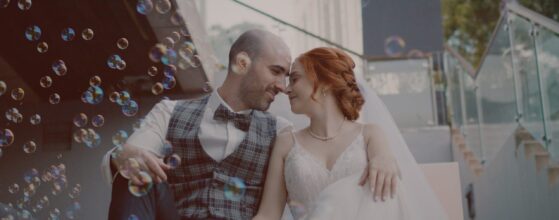 Netti és Patrik szappanbuborékok között ülnek a lépcsőn, nevetve hajolnak egymáshoz – egy játékos pillanat az esküvői filmből. Larus Restaurant Budapest wedding film