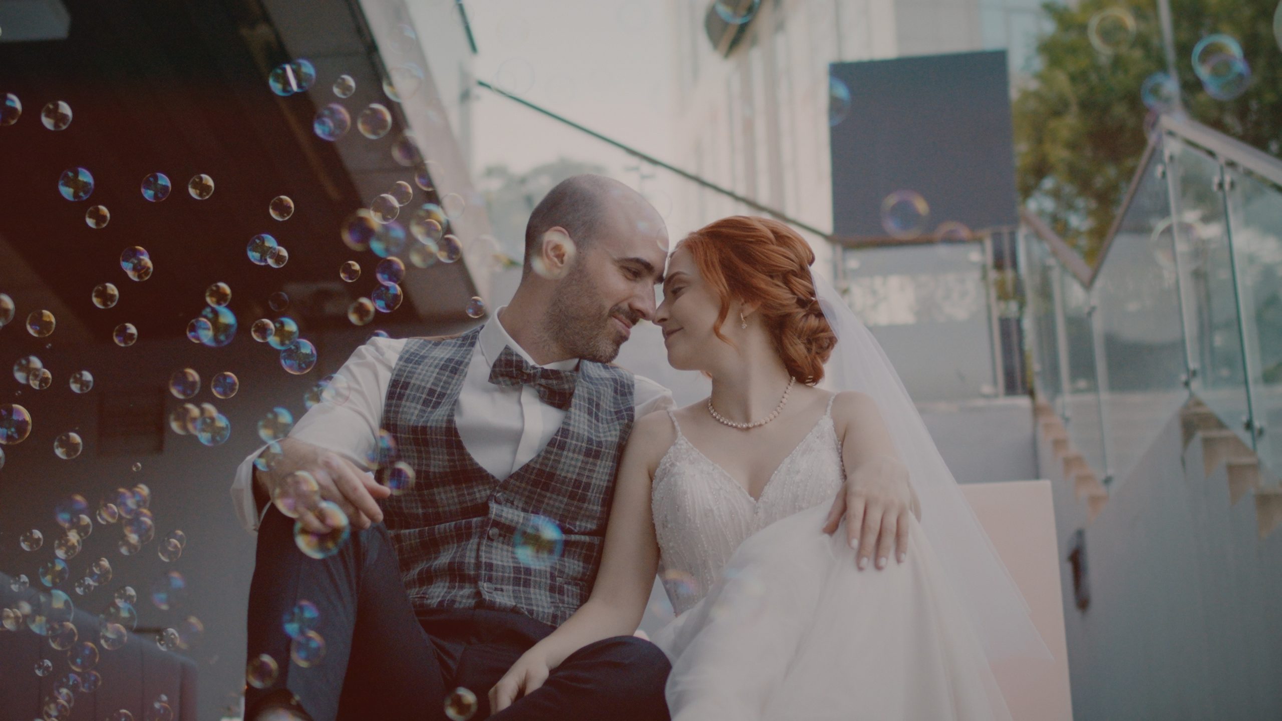 Netti és Patrik szappanbuborékok között ülnek a lépcsőn, nevetve hajolnak egymáshoz – egy játékos pillanat az esküvői filmből. Larus Restaurant Budapest wedding film