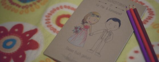 Mein Hochzeitsbuch für Mal- und Rätselspaß liegt mit bunten Farbstiften auf einer Decke bei der Hochzeit von Nicole und Daniel im Weingut am Reisenberg in Wien Wien hochzeitsvideografen