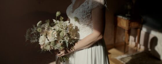 Die Braut hält ihren natürlichen Brautstrauß im warmen Morgenlicht in einem Zimmer von Schloss Obermayerhofen, bevor die Hochzeitsfeier beginnt. Schloss Obermayerhofen Hochzeitsvideograf