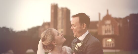 Soft evening portrait of Paula and James in front of St Audries Park in Somerset, England, with warm pastel light and a romantic wedding videography feel.