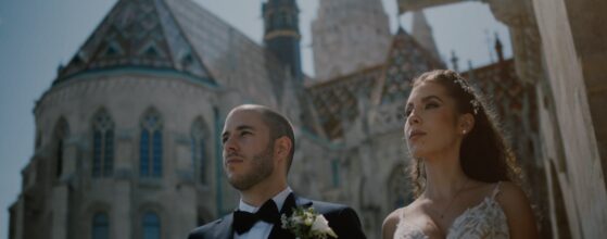 Rikarda és Krisztián elegáns városi kreatív fotózáson, történelmi templomhomlokzat előtt, az esztergomi Lóga-Tó esküvői film városi jelenete.