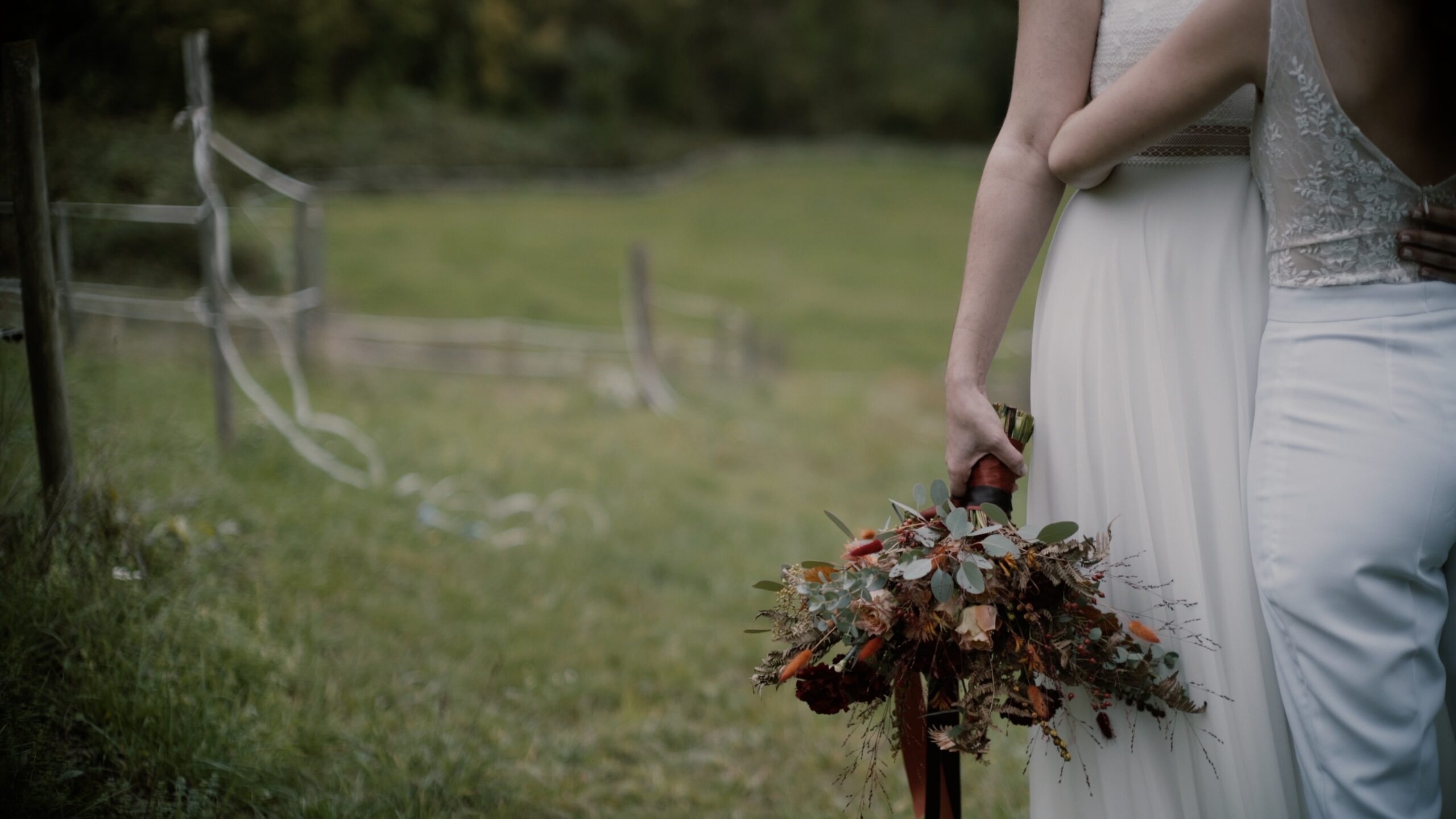 Sanny und Flo stehen in den Feldern beim Lässerhof in Stattegg während ihrer lesbischen Hochzeit in der Steiermark.
