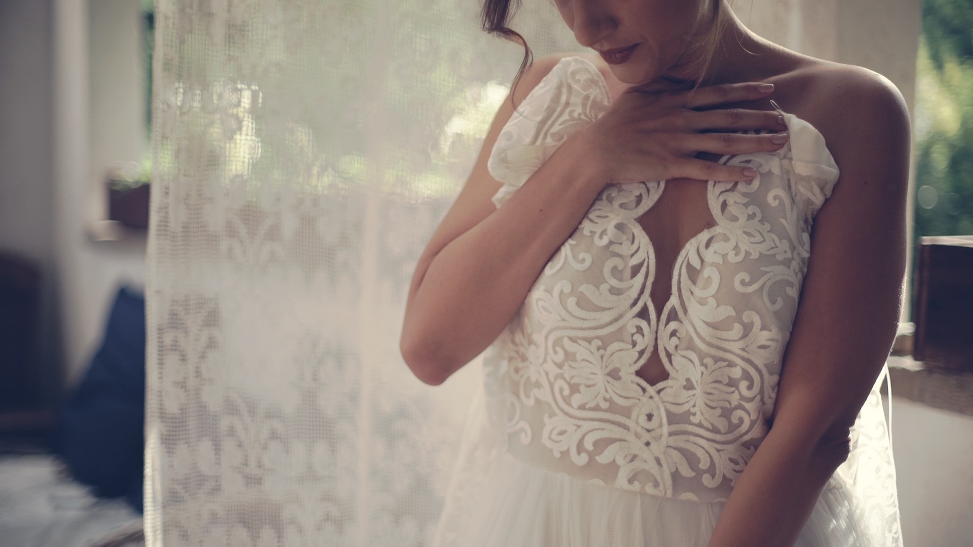 Timi a Nomád Hotel hotelszobájában csipke részletekkel díszített fehér esküvői ruhájában, napfényes ablaknál