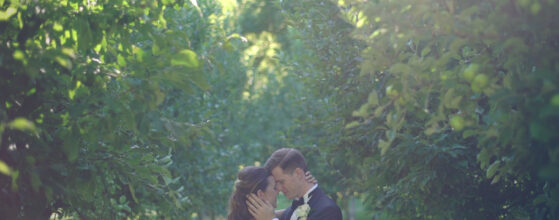 Valentina und Matthias küssen sich in einer grünen Baumallee im Schlosspark Müchlbach am Manhartsberg, umgeben von dichten grünen Blättern