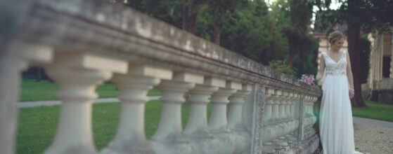 Braut Valentina steht im Hochzeitskleid an der steinernen Balustrade im Park in Wien Hermesvilla hochzeit film