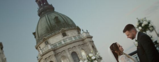 Viktória és Attila esküvői csókja az Aria Hotel Budapest tetőteraszán, háttérben a Szent István-bazilikával, naplementés esküvői film jelenet. Magyar pár budapesti esküvői videós Magyarország forgatása naplementében, természetes, filmes hangulattal.