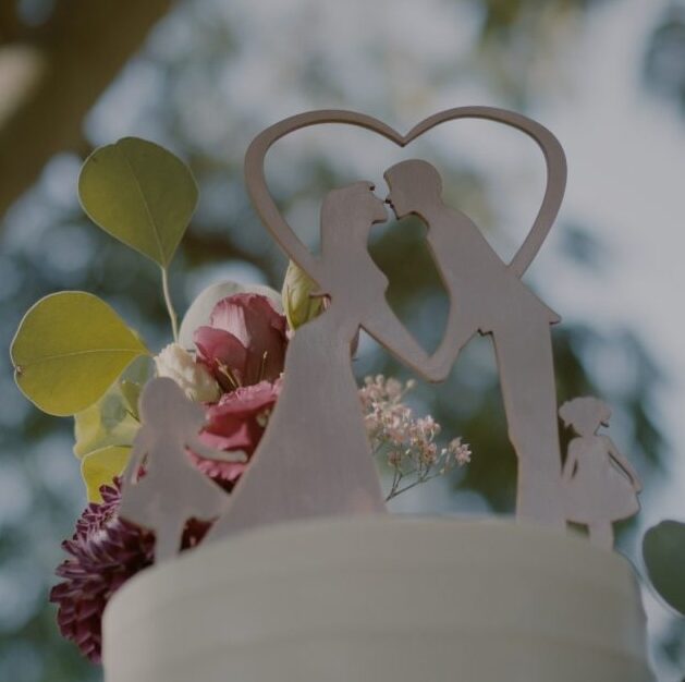 Wedding cake topper with a couple and children in a heart shape, surrounded by flowers, at Winzerhotel Kolleritsch – a soft, intimate wedding detail.