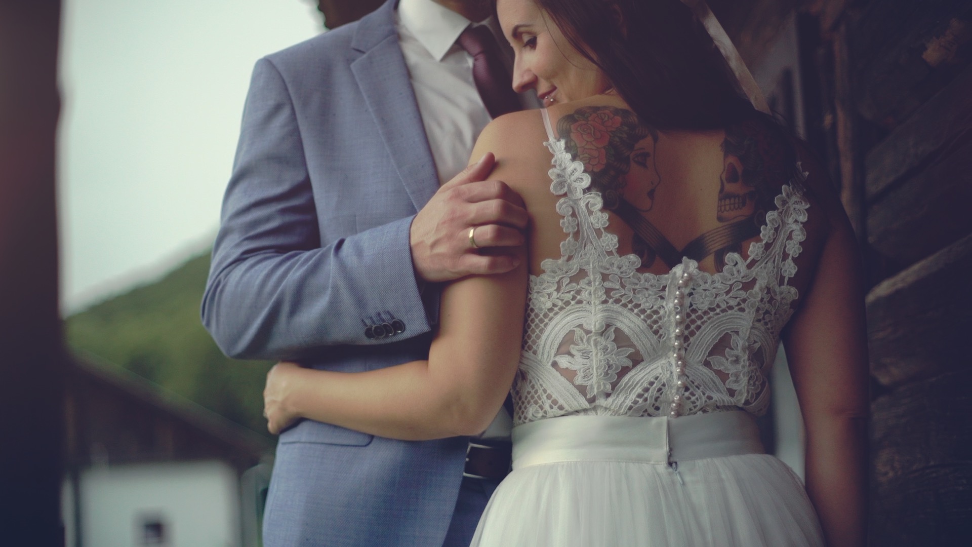 Zsófi és Peti egymást öleli az esküvői fotón, Zsófi fehér csipke ruhájában és Peti kék öltönyében a Lósi Major alatt